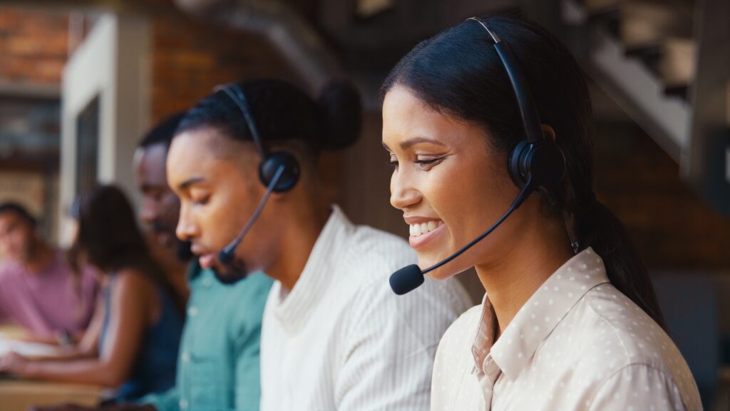 Close Up Of Multi-Cultural Customer Support Or Telesales Team In Modern Office Wearing Headsets