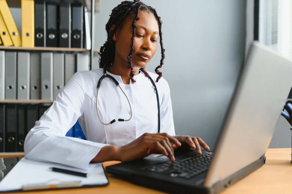 healthcare, medical and technology concept - african female doctor with laptop